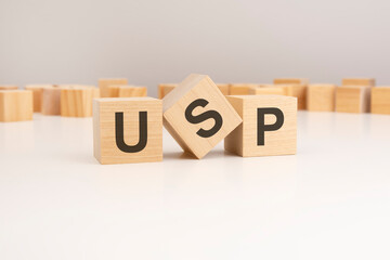 three wooden cubes with USP symbols on them. white background. in the background there are many wooden blocks of different sizes