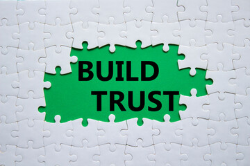 Build trust symbol. White puzzle with words Build trust. Beautiful green background. Business and Build trust concept. Copy space.