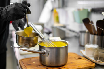 Chef hands cooking cheese sauce in the restaurant kitchen