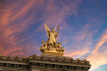 Fototapeta na wymiar Golden statue of Liberty on the roof of the Opera Garnier (Garnier Palace) against the sky at sunset. Sculpted by Charles Gumery in 1869. Paris, France. UNESCO World Heritage Site