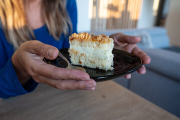 The woman holds food in her hand. the girl holds in her hands. Cake on plate.