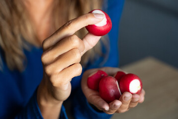 The woman holds vegetables in her hand. The girl holds an radish. Radishes in woman's hands. Red Radish