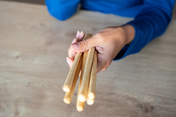 The woman holds food in her hand. Girl holds Grissini in her hands. Italian grissini holding by women.