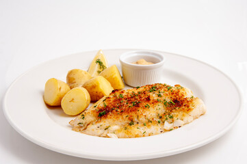 Cooked white fish with new potatoes on a white plate