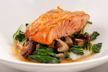 Cooked wild salmon on a bed of mushrooms and cabbage.