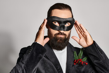 Obraz premium Masquerade, handsome bearded man in carnival mask and elegant formal wear on grey backdrop