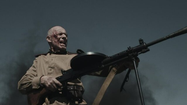 Low angle view portrait of mature Red Army soldier shouting and firing rifle, Second World War reenactment