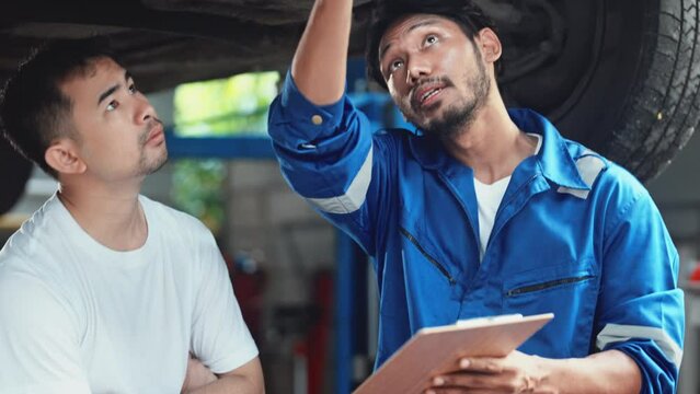 mechanic technician specialist talking with customer at car service garage.