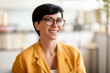 Portrait of happy middle aged woman smiling at camera indoors