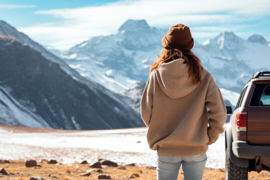 Traveler woman next to her car observing the snowy mountains