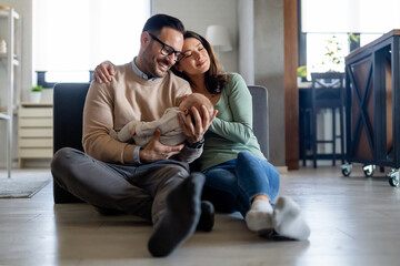 Fototapeta premium Peaceful young married couple enjoying being family, parents, holding new born baby in arms