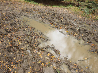Fototapeta na wymiar Flooded country lane with thick mud and lots of rain water across the width of the track