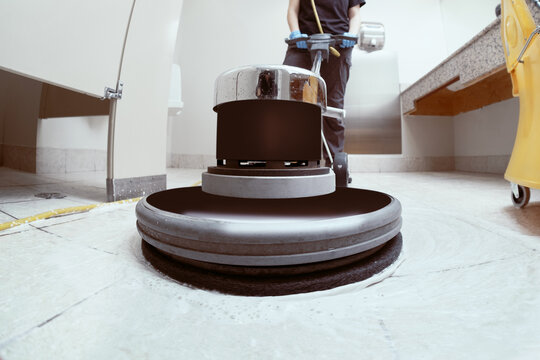 unrecognizable woman scrubbing the floor of a toilet with a machine