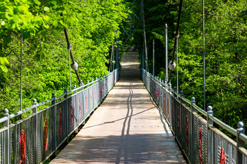 A beautiful metal pedestrian bridge surrounded by green foliage. Obninsk, Russia