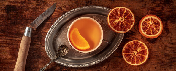 Orange tea with fresh and dried oranges panorama, on a vintage tray on a dark rustic wooden background, top shot