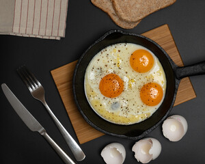 Scrambled eggs in a frying pan on a black background