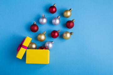 Christmas gift box with colored beads on the blue background. Copy space. Top view.