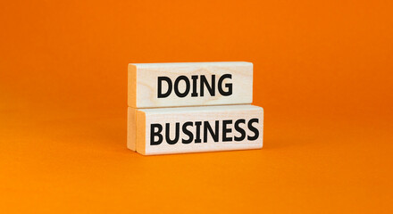 Doing business symbol. Concept words Doing business on beautiful wooden block. Beautiful orange table orange background. Business, motivational Doing business concept. Copy space.
