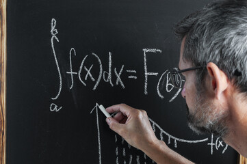 Teacher writing mathematics formula on a blackboard close up