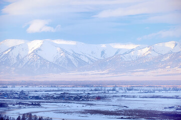 Cold snowy mountain landscape at sunset. Panoramic view of snowy mountain peaks and slopes of North Chuyskiy ridge at sunset. Russia, Siberia, Altai mountains.