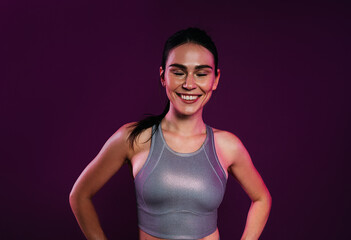 Portrait of a cheerful sportswoman.in silver fitness wear against a magenta backdrop