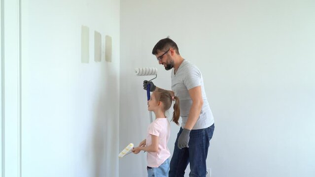 Father and little daughter choose wall paint on test of different colors at home in flat. Family doing renovations. Repair concept, molar work