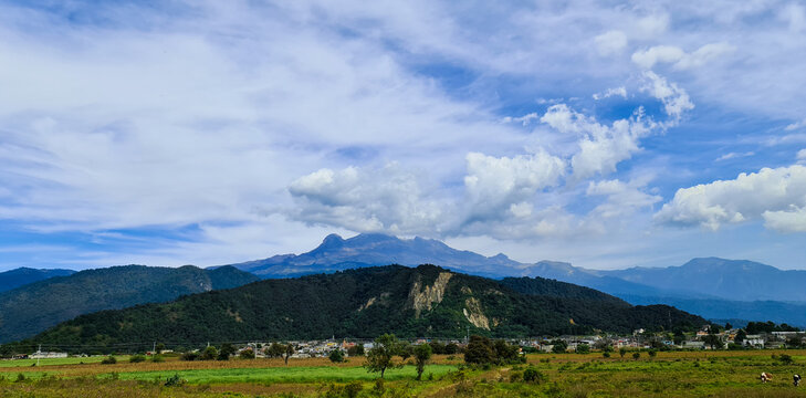 volcán iztaccihuatl entre  nubes y cerros verdes