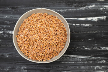 Wholegrain uncooked raw spelt in ceramic bowl