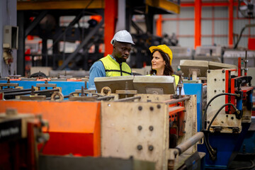 Team of young male and female engineers in a metal sheet factory Responsible work is being...