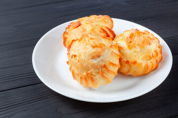 Golden profiteroles filled with cream, served on white plate on dark table. a delightful dessert pairing for any occasion