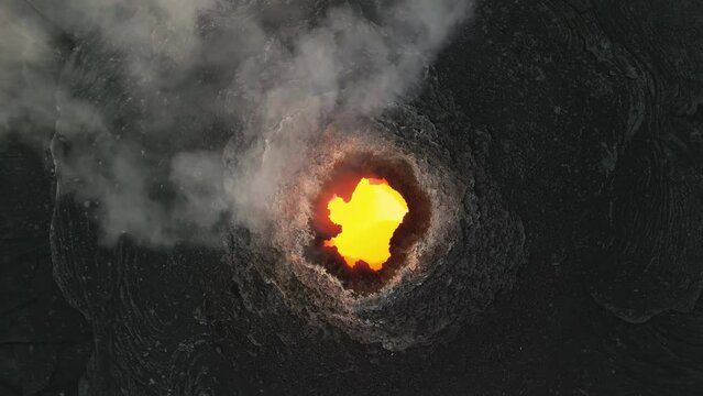 Erta Ale, Danakil Depression, Ethiopia. Aerial view of active volcano smoking and lava activity. Cinematic drone footage of volcanic pit at sunset. Famous adventure travel destination landmark.