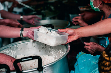 Refugees' hands are receiving food from philanthropists: the concept of hunger problems for the poor