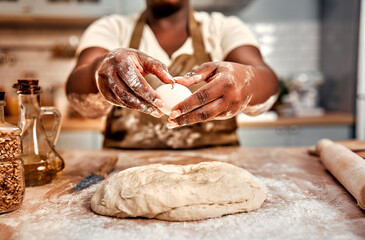 Ingredients for baking. Close up of female hands in flour adding raw egg to dough before kneading...