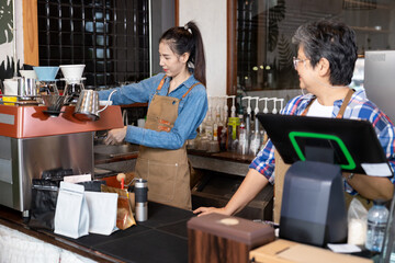 An elderly Asian retiree stands at the counter at a takeout machine. Looking at the barista's...