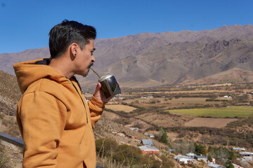 close-up of a brown latin man in solitude and relaxed, drinking mate enjoying the landscape from a...