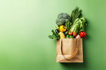 Poster Purchases or delivery of healthy food. Healthy vegan vegetarian food in a paper bag, fruits and vegetables on a green, copy space. Food supermarket and the concept of pure vegan nutrition. © Valentin