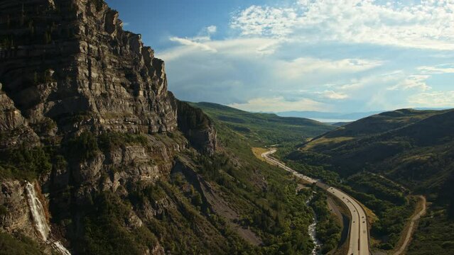 Aerial flyover view of distant cars driving on highway in valley / Provo Canyon, Utah, United States