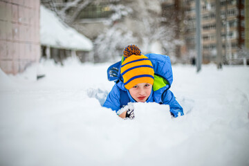 Fototapeta na wymiar Cute little boy having fun with snow in winter park. Happy child playing with snow in winter park