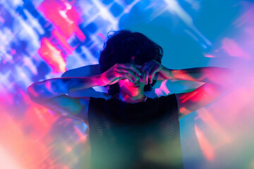 Latin man covering his face with hands in neon lights