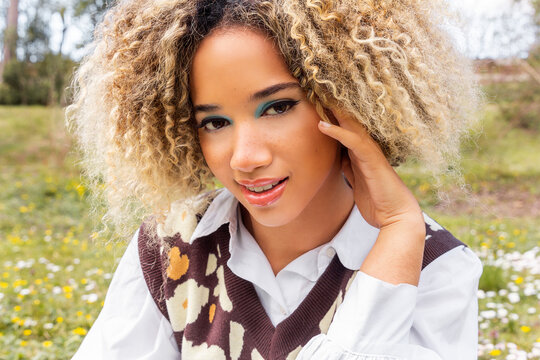 Young afro woman with turquoise eyeshadow and flower-patterned vest