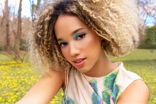 Ethnic woman with vibrant eyeshadow in flower park