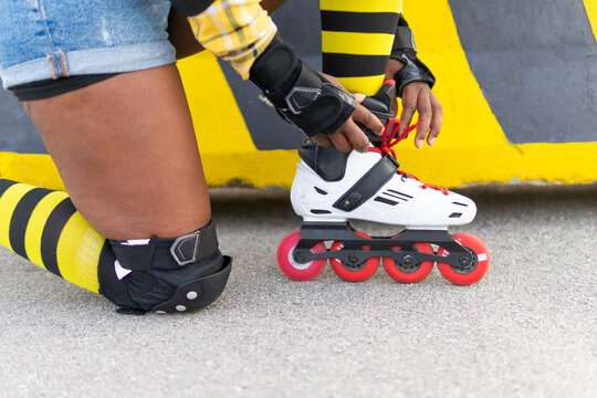 Woman Wearing Roller Skate Shoe While Kneeling At Skate Park