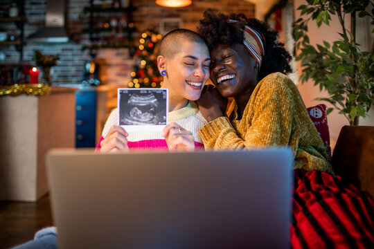 Lesbian couple joyfully sharing their ultrasound image, celebrating their upcoming parenthood