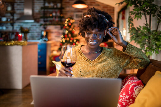 Young woman working on her laptop in a cozy living room with Christmas decorations
