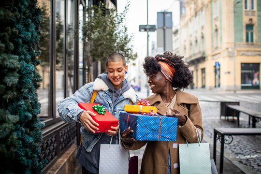 Lesbian couple excitedly exchanges gifts on a city street