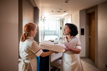 Two hotel housekeepers sharing a light moment while exchanging fresh linens