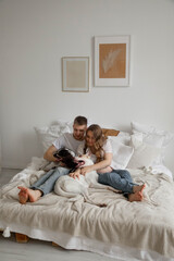 Couple in love, pregnant girl and guy with dogs on bed, bright photo