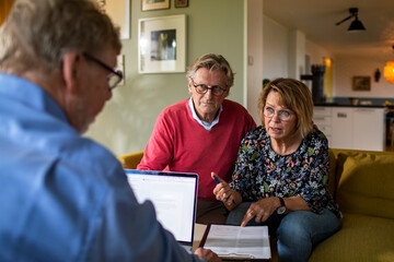 Elderly couple discussing their retirement plan with a financial advisor at home