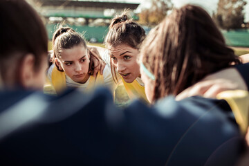 Intense huddle of female football players strategizing on the field