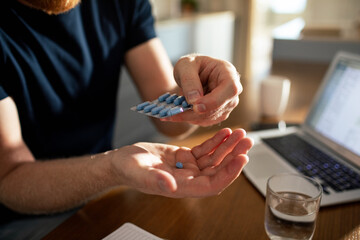 Close up of hands of young man with pills with water in the kitchen - obrazy, fototapety, plakaty
